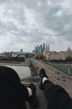一个人坐在窗台上，俯瞰着多云天空下繁华的城市景观、河流和摩天大楼