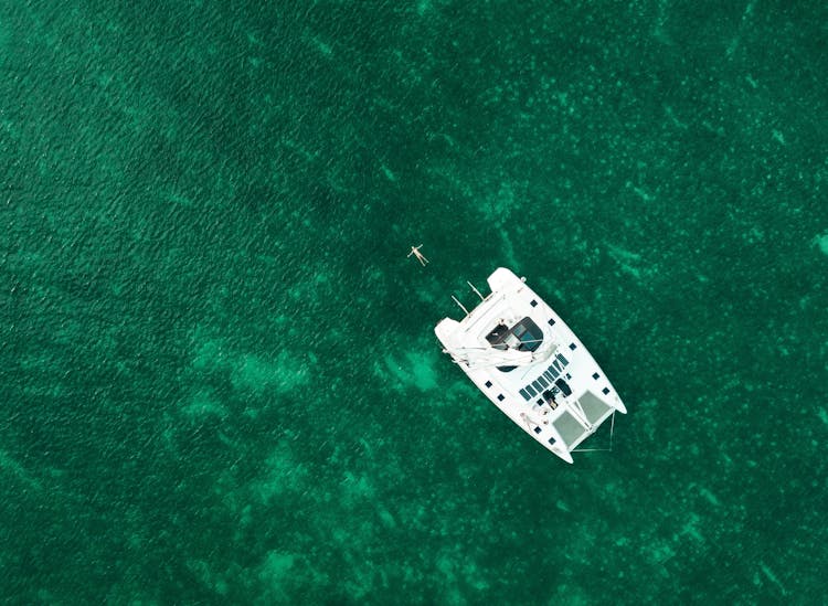 Modern Boat Floating In Emerald Water Of Clear Sea