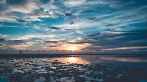 A tranquil beach sunset with vibrant colors and dramatic clouds reflecting on the water.