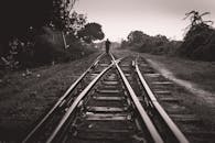 一个孤独的人影，沿着穿越铁轨，行走在喜怒无常的黑白风景中