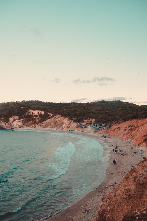 Free A tranquil view of a sandy beach and rugged cliffs in Türkiye, captured at dusk. Stock Photo