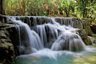 在郁郁葱葱的森林中，一条瀑布长时间宁静地倾泻而下