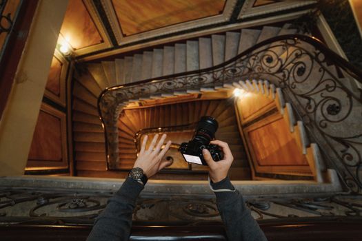 Photographer capturing a stunning spiral staircase with ornate metal railing from a high angle view.