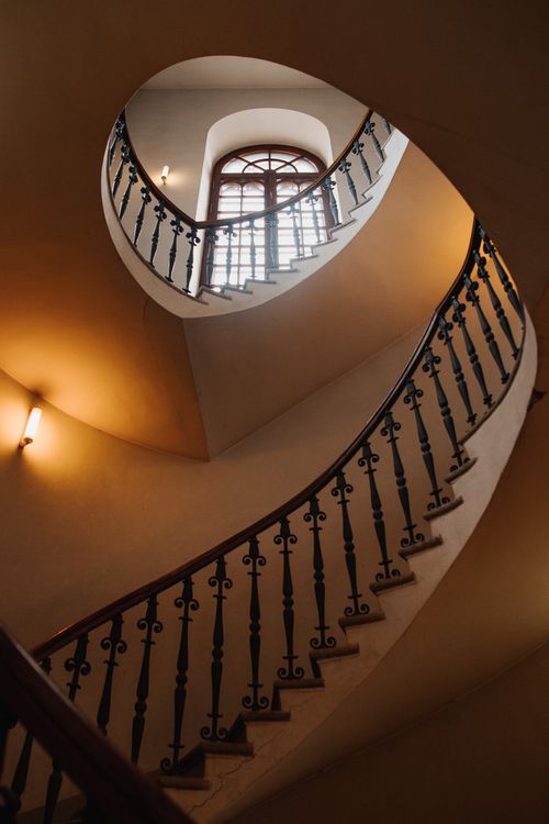 Free A visually captivating spiral staircase with intricate iron railings and a bright window above. Stock Photo