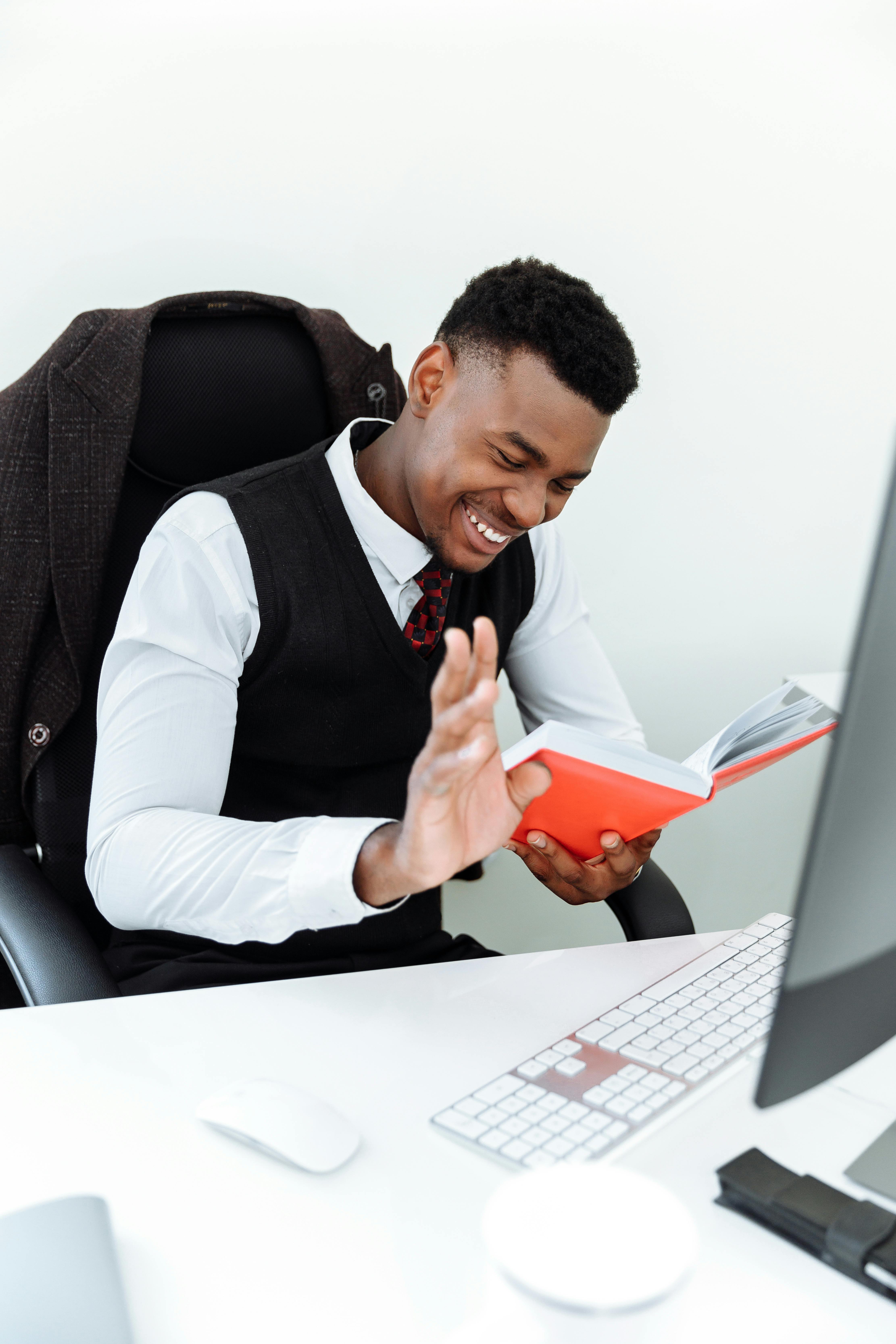 man in white dress shirt and black necktie holding orange smartphone