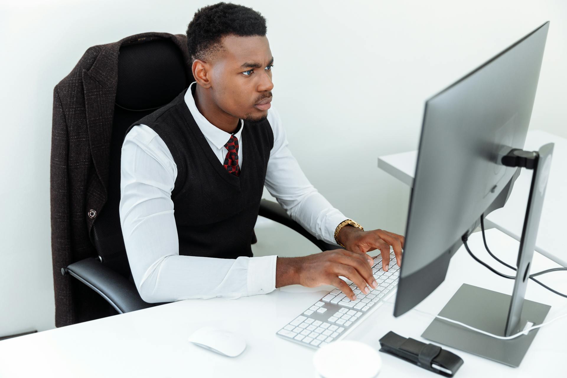 Professional man intensely working on a computer at his office desk, focused and determined in a business environment.