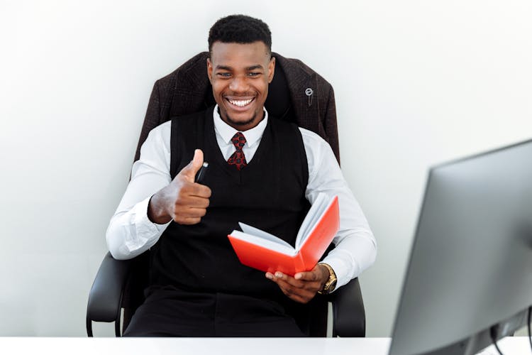 Man Sitting On An Office Chair And Holding A Notebook