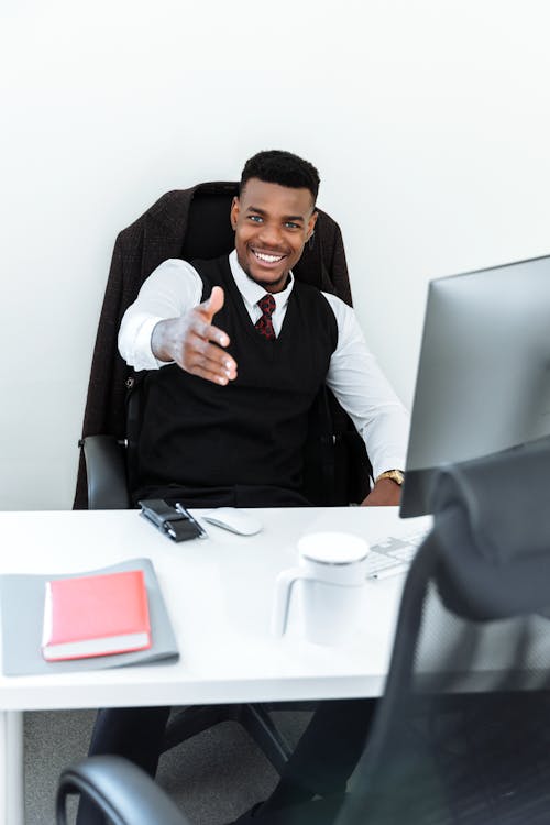Free Man in Black Vest Sitting Behind a Desk Stock Photo