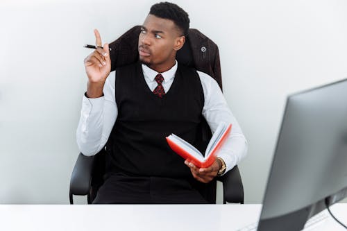 Man in Black Vest and White Dress Shirt Sitting on Black Leather Armchair