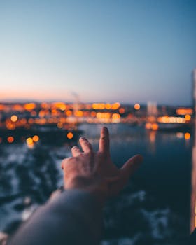 黄昏时分，一只手伸向灯火通明的城市，捕捉着暮色渐染的宁静