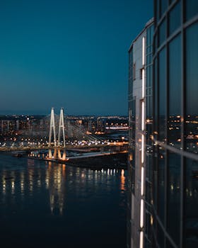 在黄昏的天空下，照亮的吊桥横跨河流，映衬着城市天际线