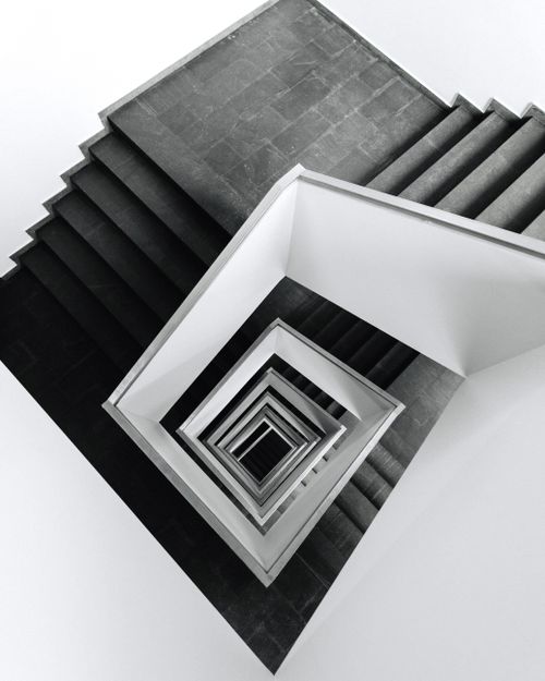 Free Artistic black and white overhead shot of a spiral staircase creating a geometric pattern. Stock Photo
