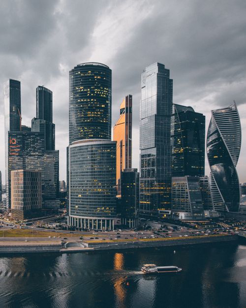 Free A dramatic aerial shot of Moscow's skyscrapers reflecting over water under a cloudy sky. Stock Photo
