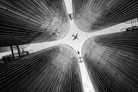 Black and white shot of an airplane flying over tall urban structures in Vietnam.
