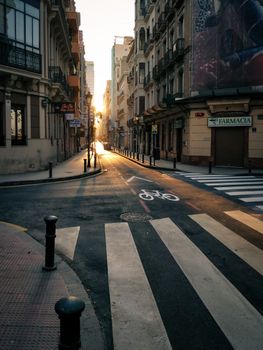 Golden sunlight illuminates a narrow street in Alicante, Spain, creating a warm and inviting ambiance.
