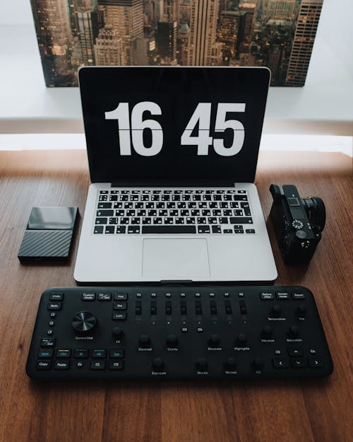 Silver Laptop Beside Black Camera and Black Console for Photo and Video Editing