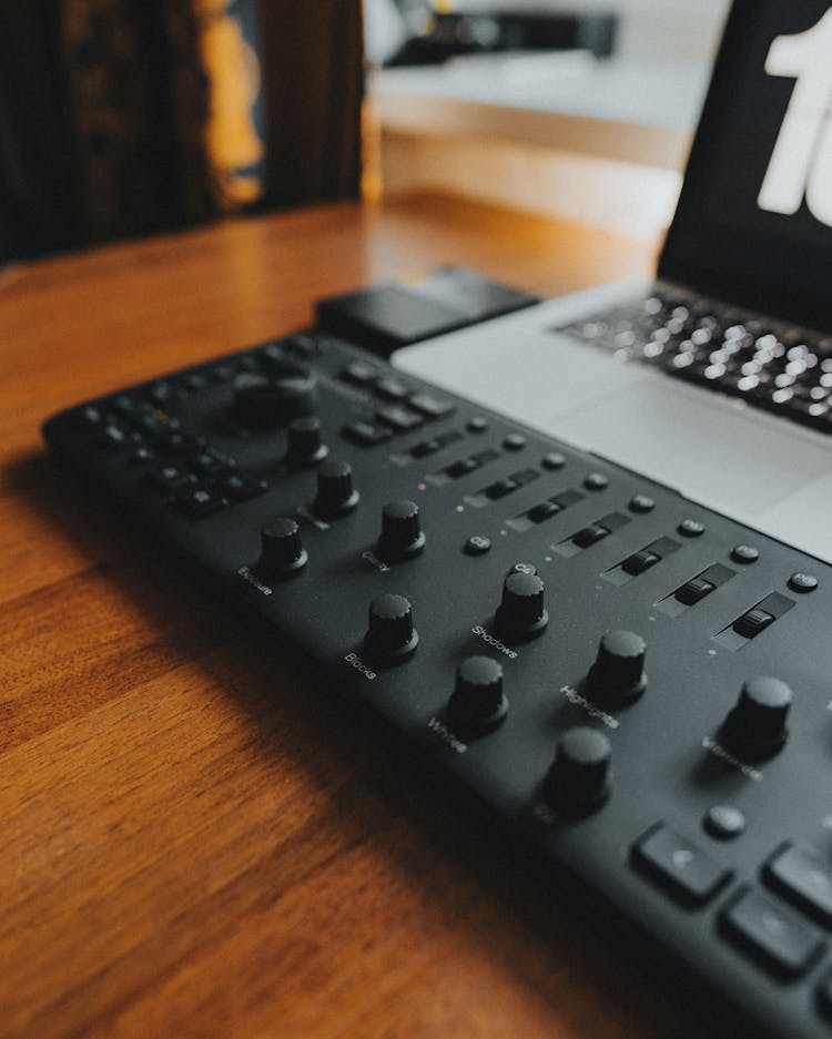 Black Console For Editing Beside A Laptop On Wooden Table