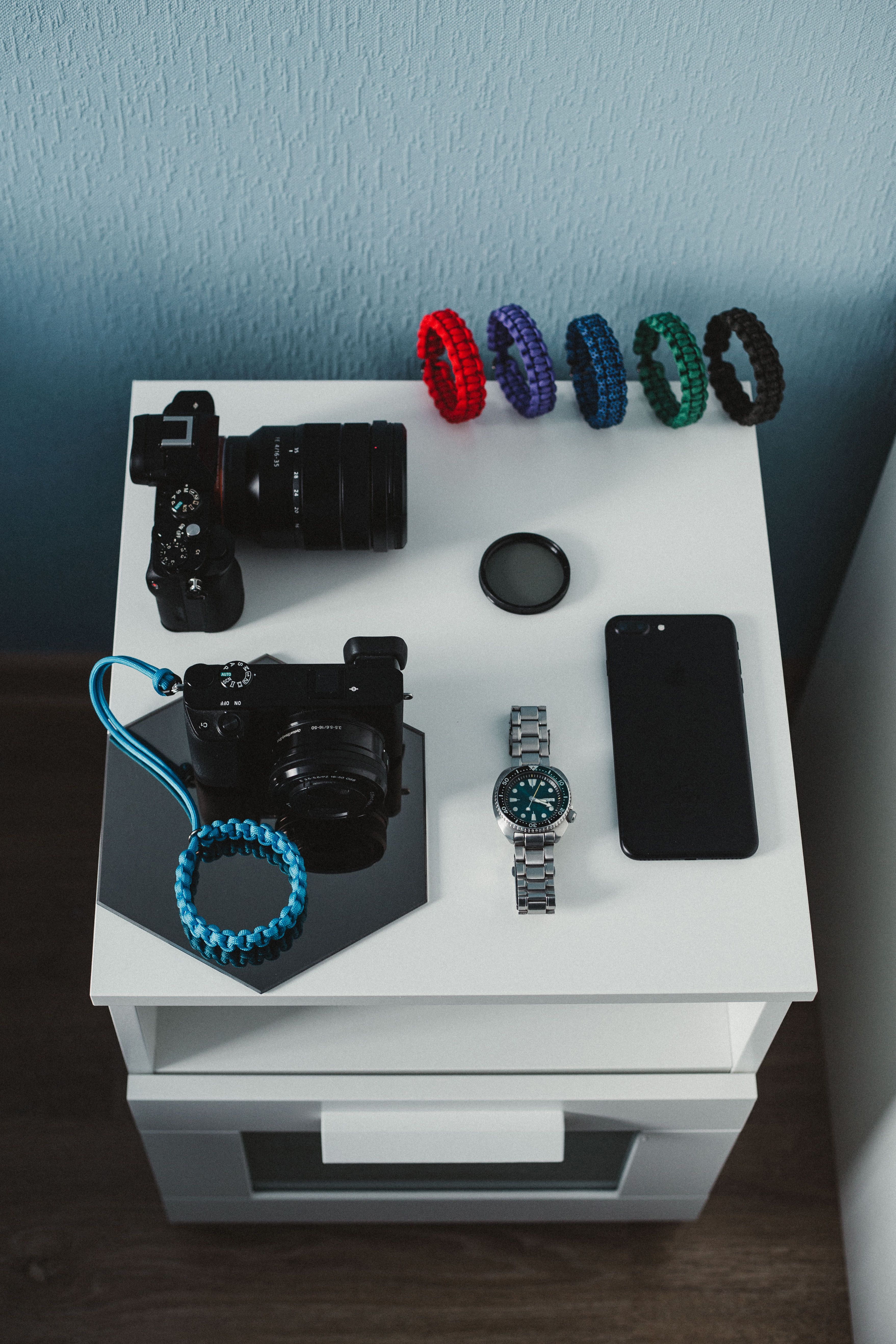 Stylish flat lay of camera equipment and accessories on a chic nightstand setting.