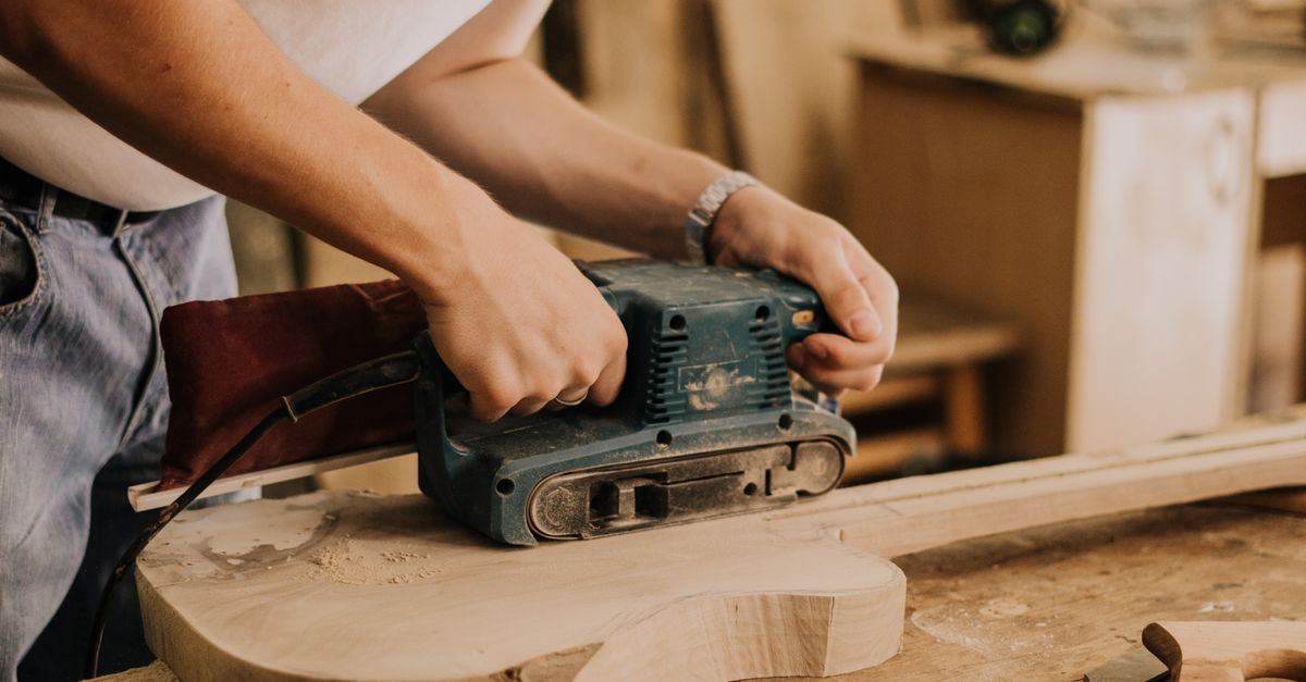 A Man Using a Sanding Machine to Polish a Guitar · Free Stock Photo