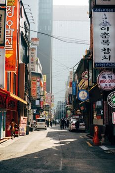 首尔热闹的街道上，充满活力的标志林立，人们在高层建筑间穿行