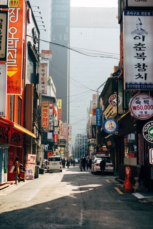 Free Lively street in Seoul with vibrant signs and people walking amidst tall buildings. Stock Photo