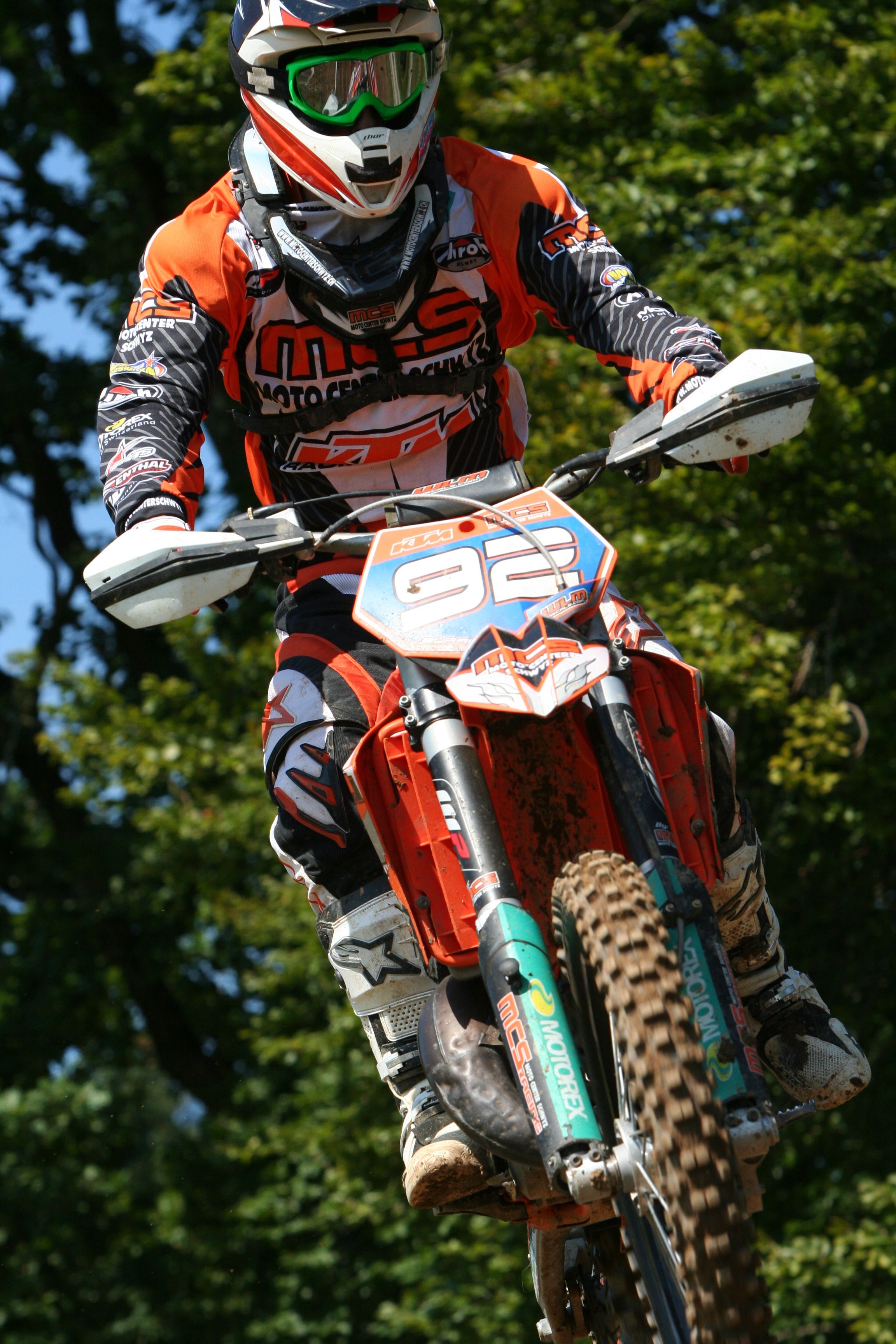 Exciting motocross jump showcasing a rider in mid-air during a daytime race.