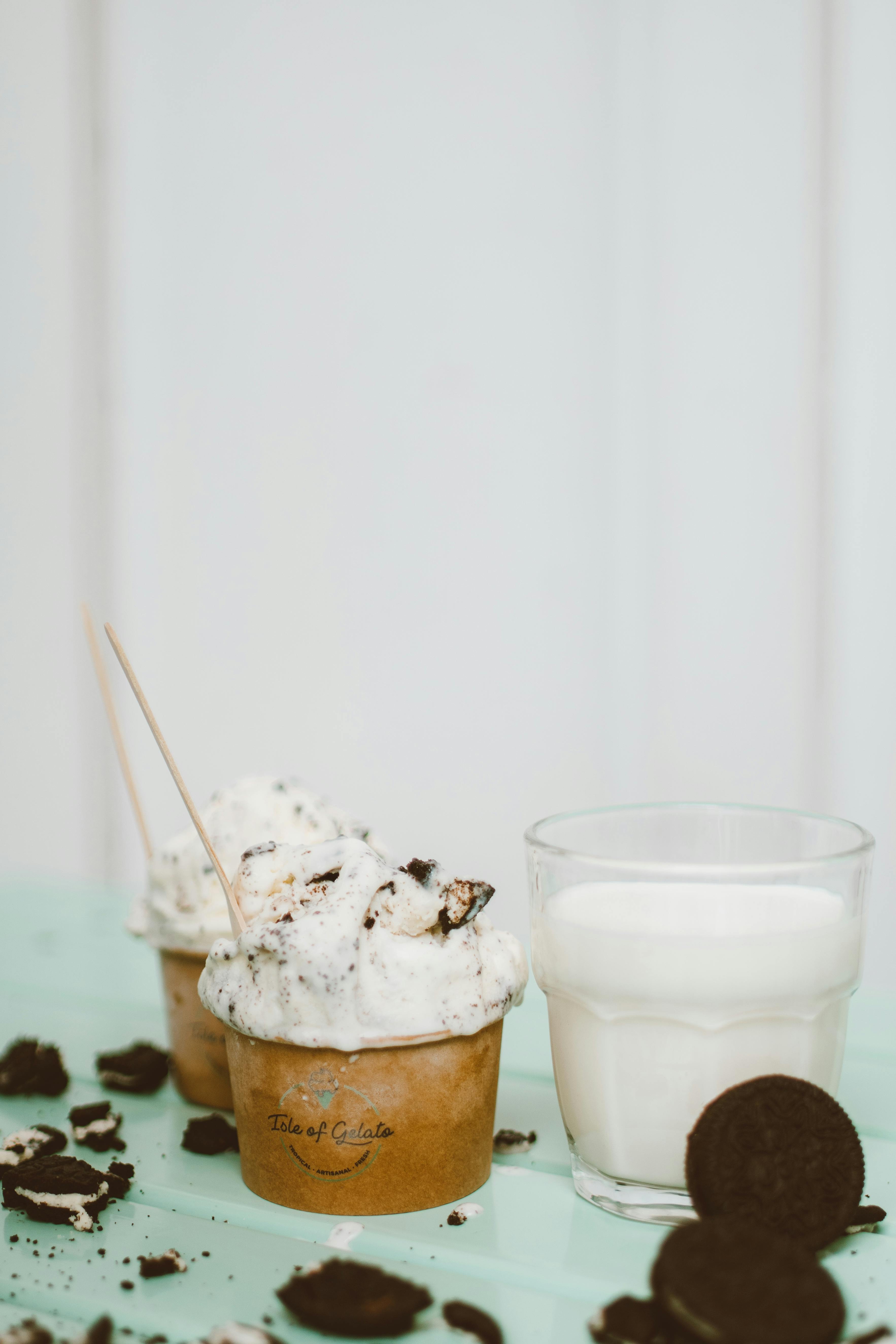 浅色背景上，美味的饼干和奶油冰淇淋搭配着一杯牛奶