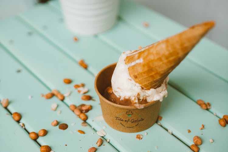 Ice Cream In Paper Cup Decorated With Cone And Peanuts