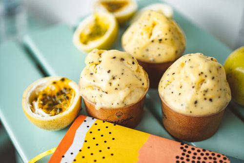 Free Close-up of creamy passion fruit gelato with fresh fruit garnishes on a colorful table. Stock Photo