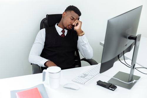 Free A man in business attire resting his head at an office desk, displaying workplace fatigue. Stock Photo