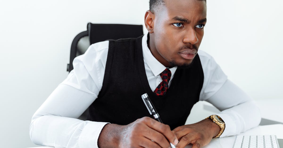 A person intensely focused on a laptop screen, with notes and a coffee cup on the desk