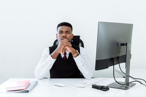 Free Focused man in business attire at office desk with computer and notepad. Stock Photo