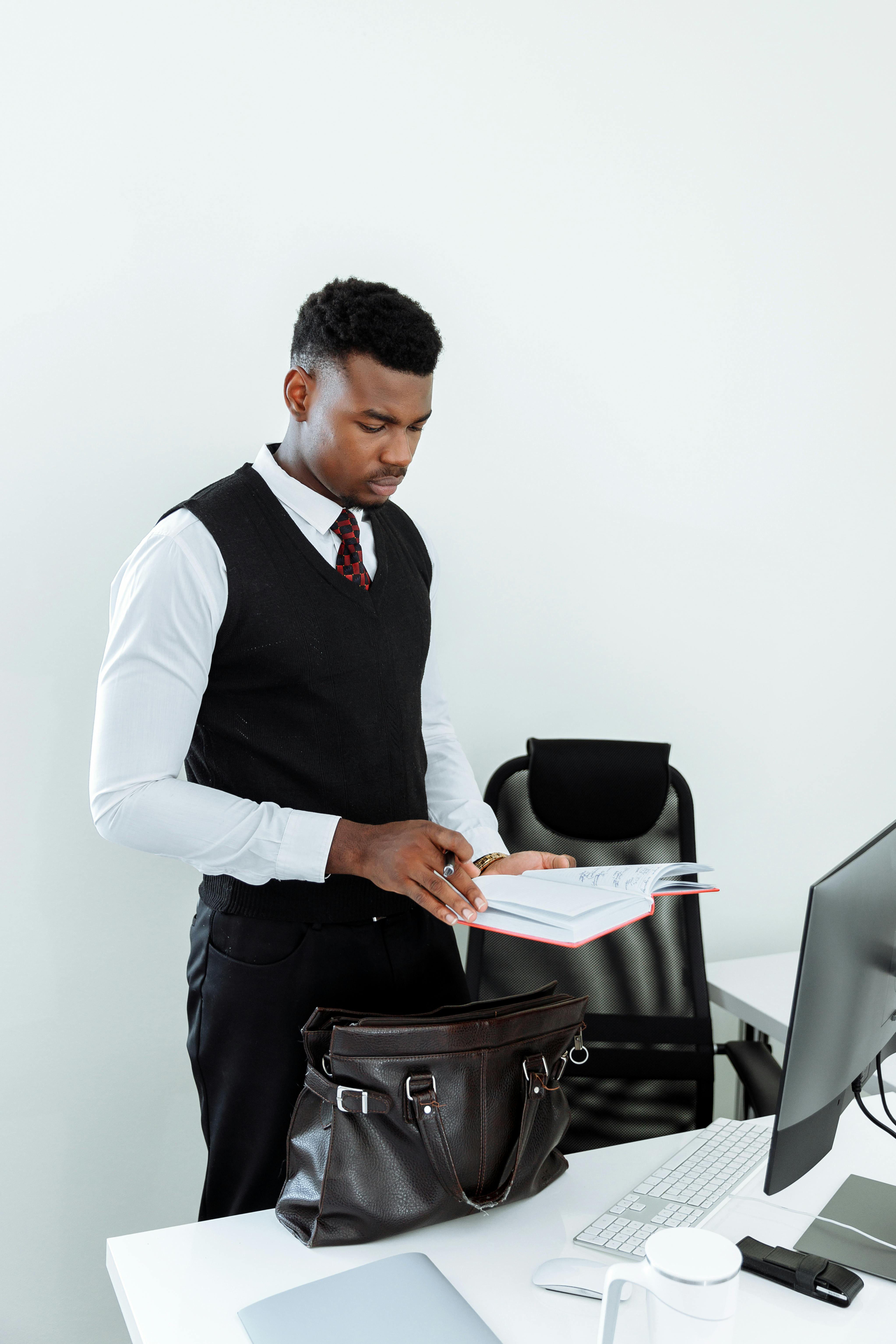 man in black vest and white dress shirt holding white printer paper