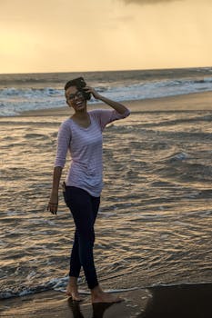 Smiling woman enjoying a barefoot beach walk during a stunning sunset at the Indian seashore.