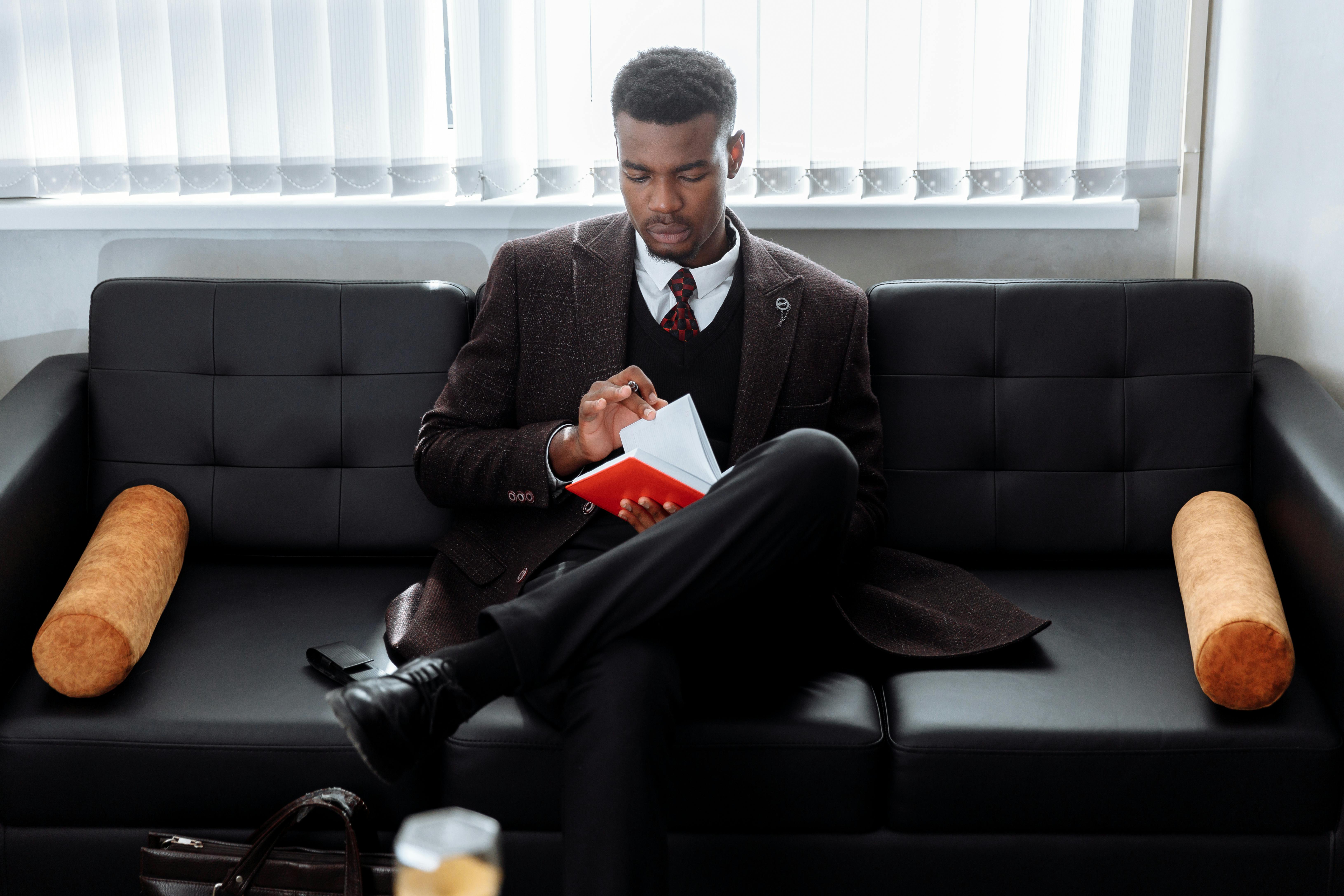 man in black suit sitting on black couch