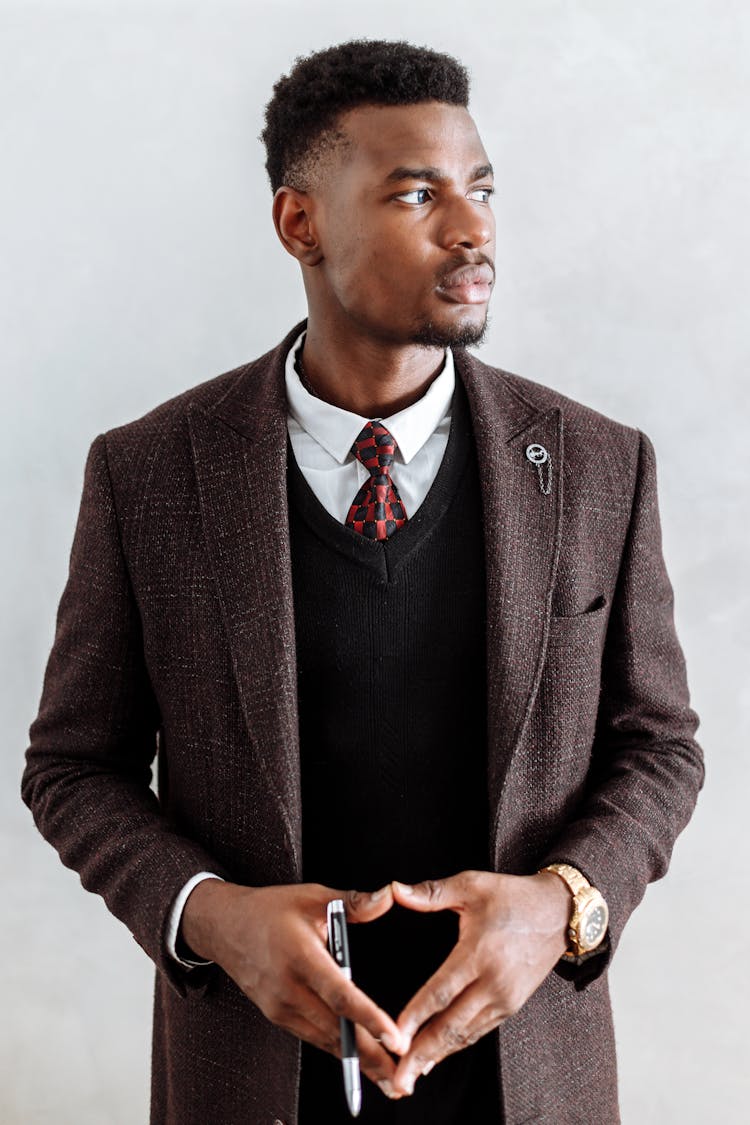 A Man In Brown Suit Looking With A Serious Face