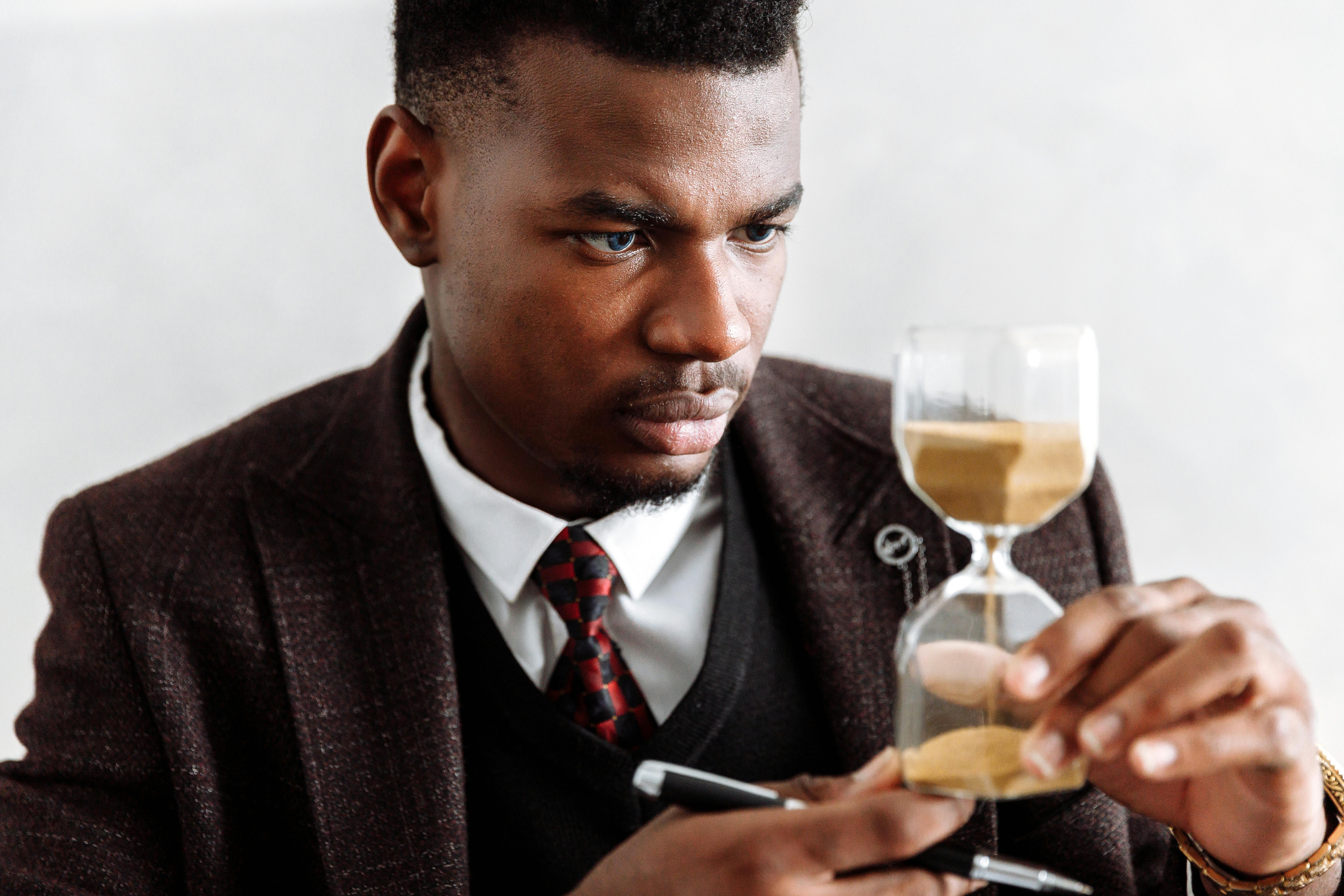 man in black suit jacket holding clear wine glass