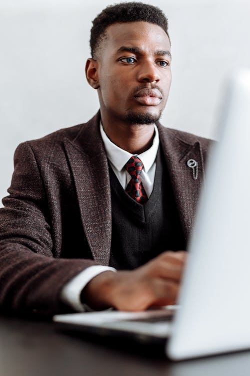 Man In Black Suit Jacket Menggunakan Macbook