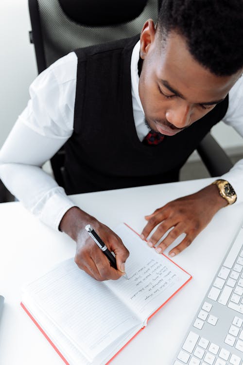 A Man Writing on White Notebook