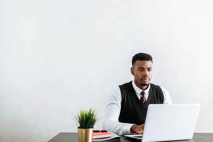 A Man Using A Laptop In The Office