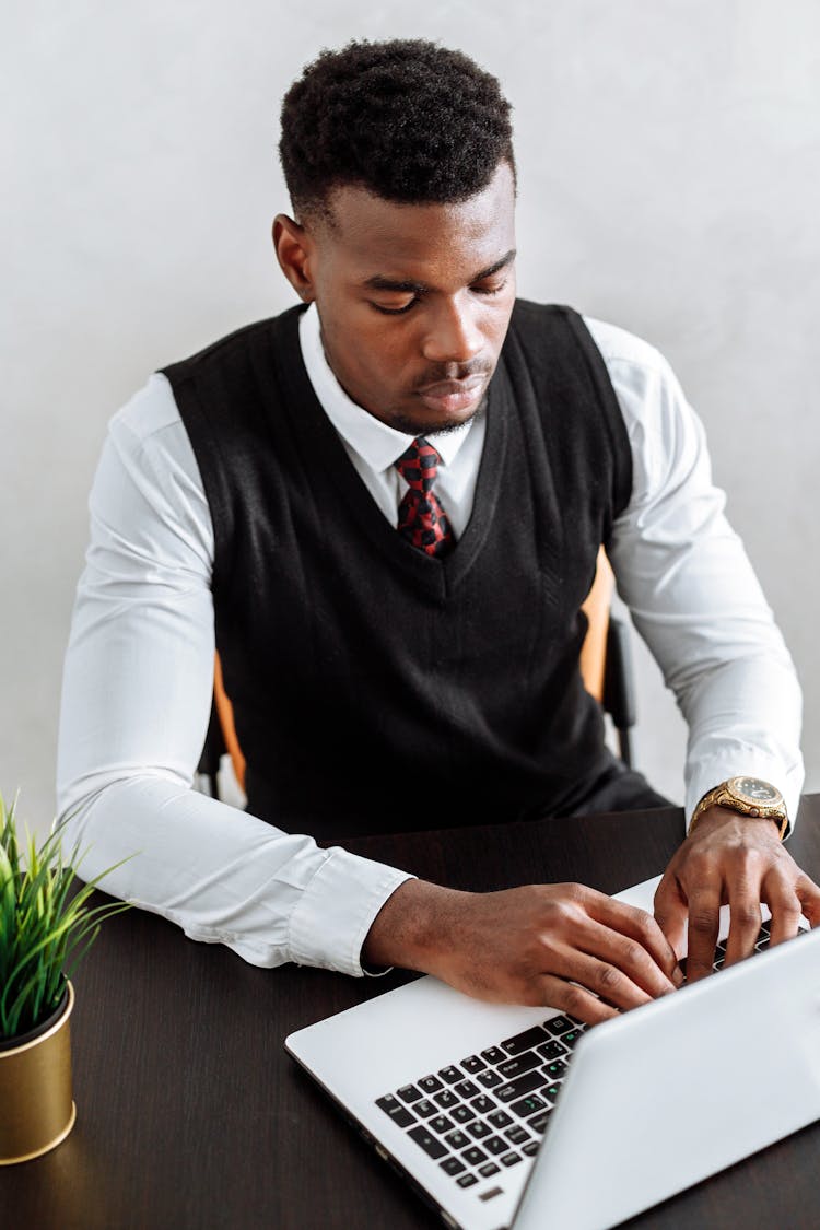 Man In Black Vest Using A Laptop