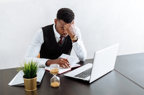 Homme En Gilet Noir Et Chemise De Ville Blanche à L'aide De Macbook Pro