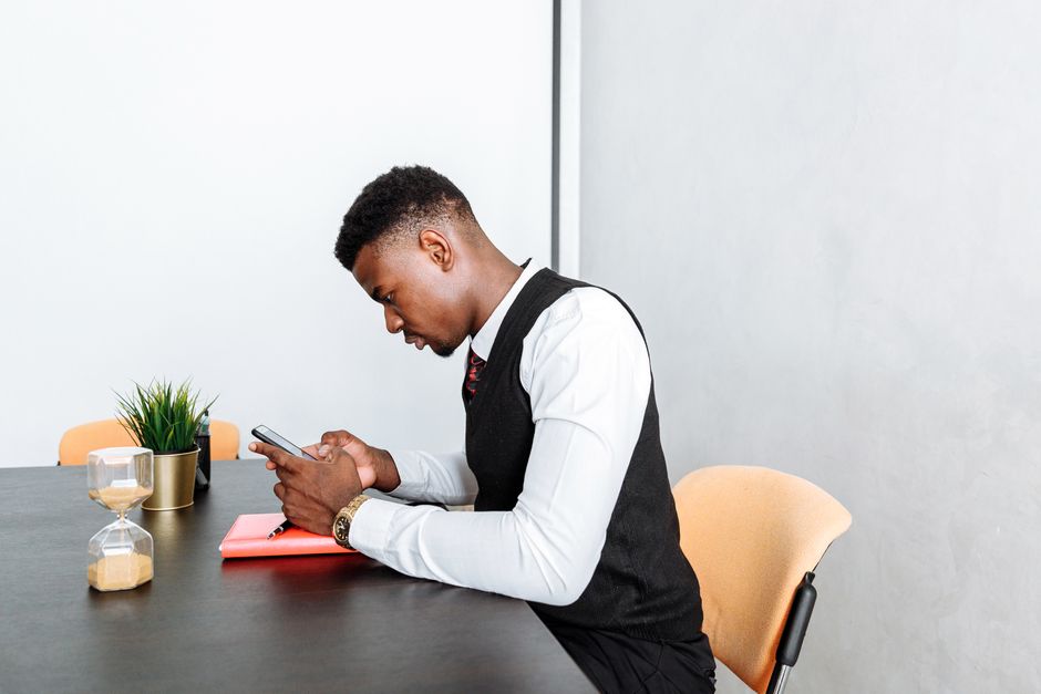 Business professional concentrating on smartphone work tasks in a modern office setting with a white background. Business professional concentrating on smartphone work tasks in a modern office setting with a white background.