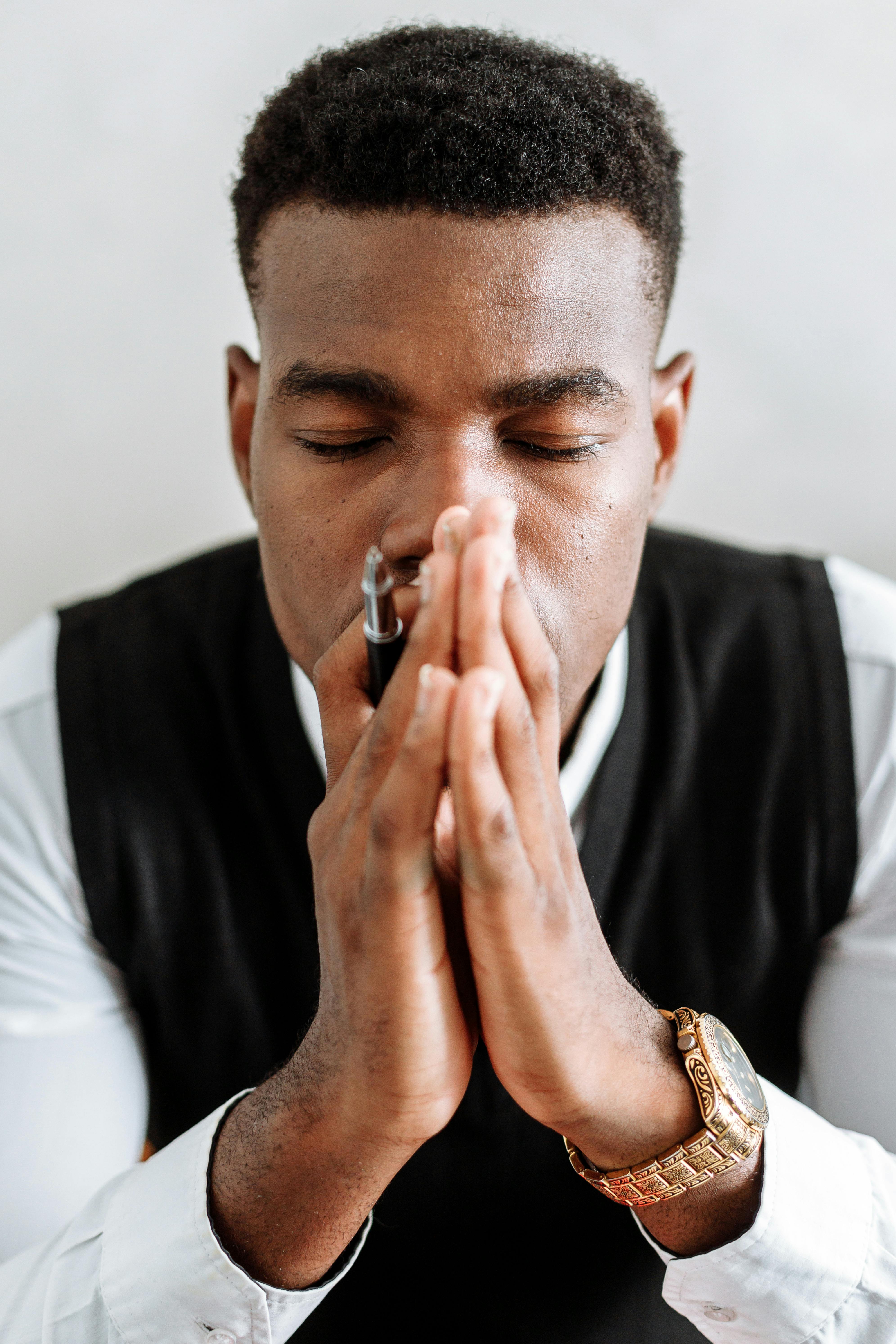 man in black suit holding his face