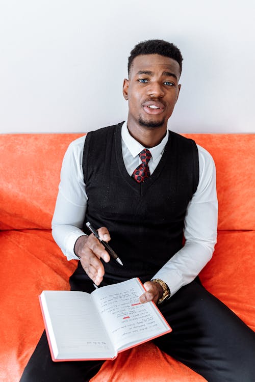 Free A Man in Business Attire Writing on a Journal Stock Photo