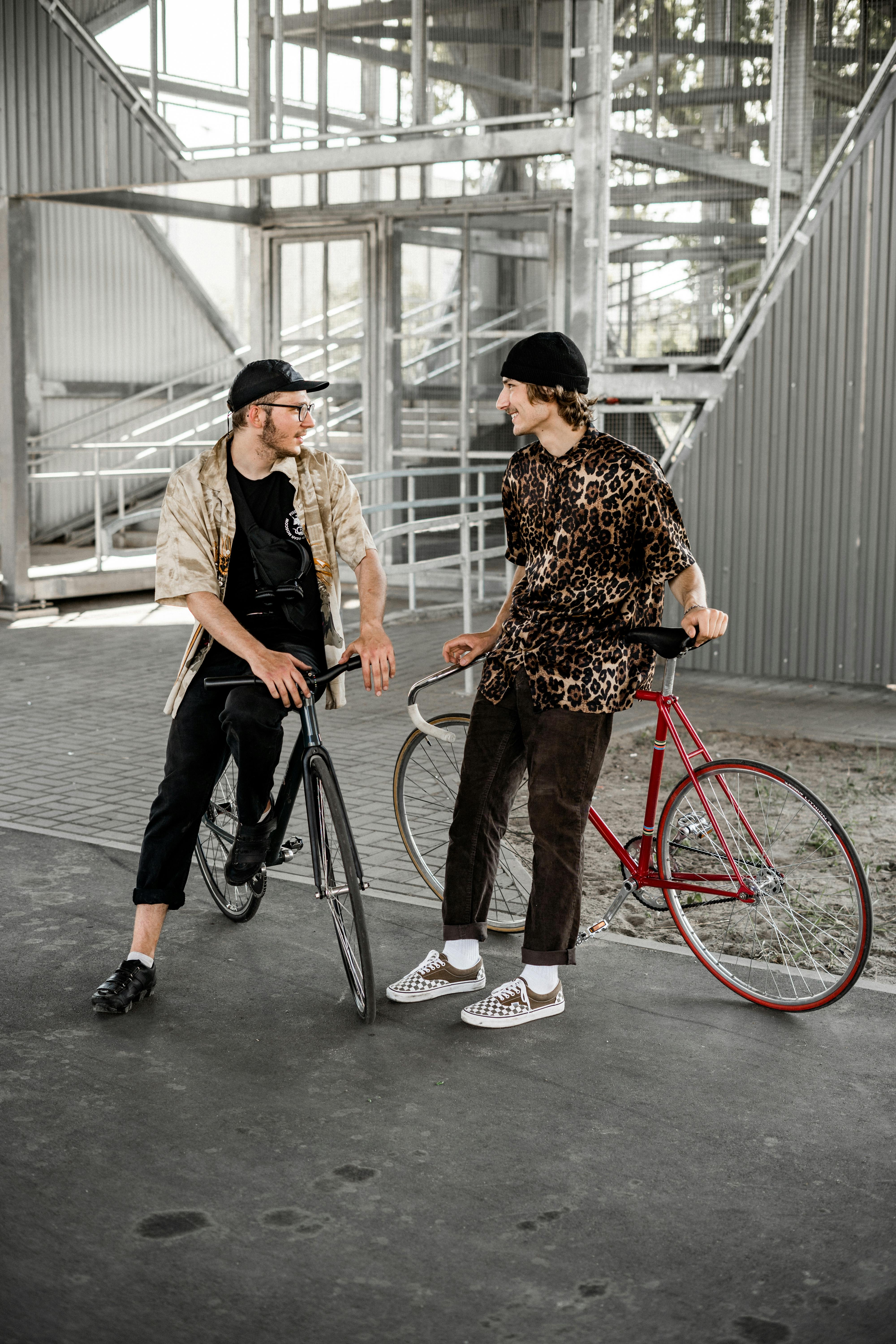 在现代城市环境中，两名时尚男子骑着自行车聊天