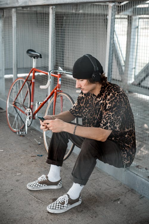 Man Sitting on Gutter While Listening to Music