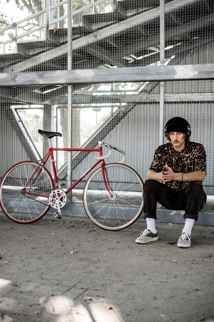 Man Sitting On Gutter Near A Bike