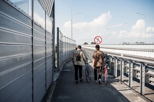 Men Walking Their Bicycles on the Roadside