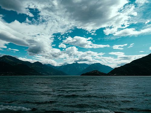 Free Scenery of rippled sea water surrounded by mountains under cloudy sky in windy weather Stock Photo